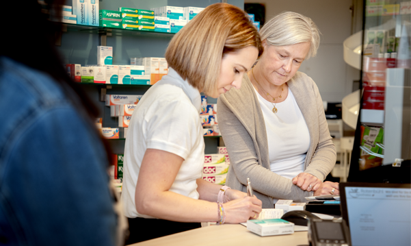 Apothekerin in der Rotenbühl Apotheke notiert sorgfältig Informationen während der Beratung einer älteren Kundin, was die persönliche und detailorientierte Kundenbetreuung verdeutlicht.