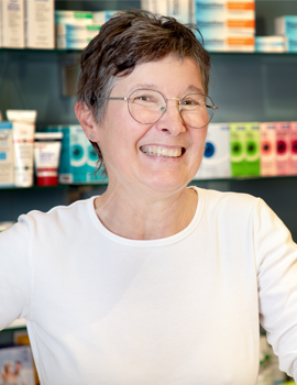 Freundliche Mitarbeiterin der Rotenbühl Apotheke mit einem warmen Lächeln, steht im modernen Apothekeninterieur, repräsentiert das engagierte und kundenorientierte Team.